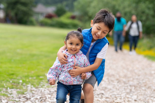 due bambini piccoli e i loro genitori che se ne andavano nella natura - chasing women men couple foto e immagini stock