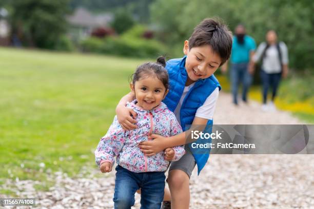 Two Young Kids And Their Parents Walking Out In Nature Stock Photo - Download Image Now