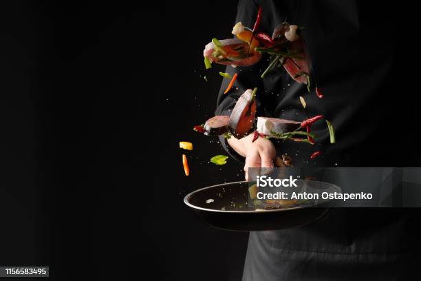 Chef Cook Fry Fish With Vegetables On A Griddle On A Black Background Horizontal Photo Sea Food Healthy Food Oriental Cuisine Baner Stock Photo - Download Image Now