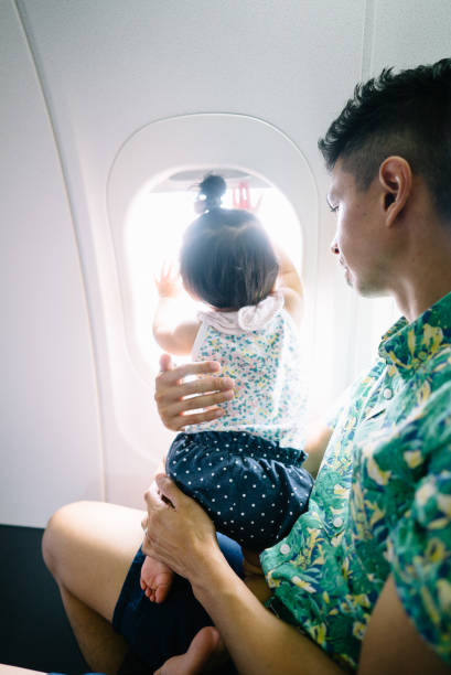 istock Daughter being held by father on a plane by the window 1156593377
