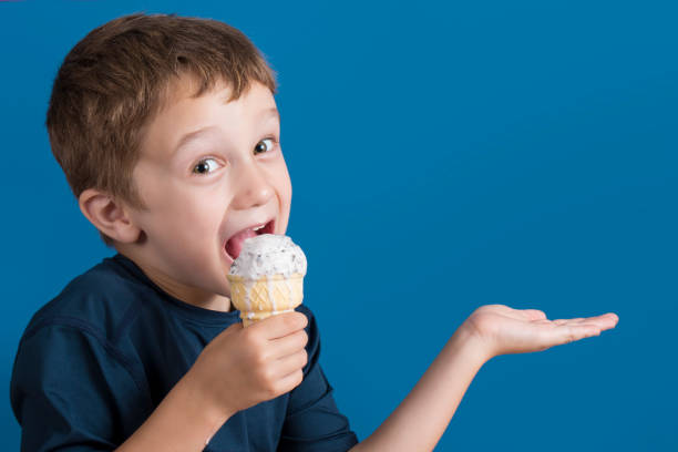 Boy eating an ice cream cone on a blue background