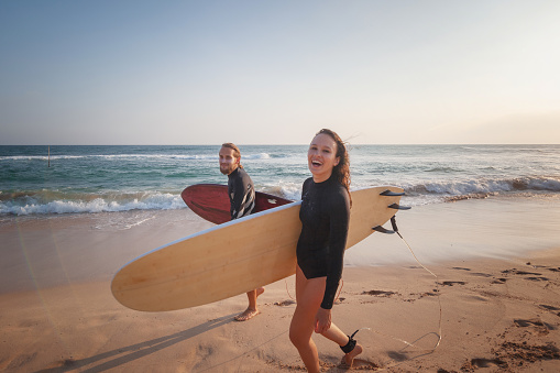 Young couple of happy smiling surfers on ocean coast, sport active lifestyle vacation travel concept
