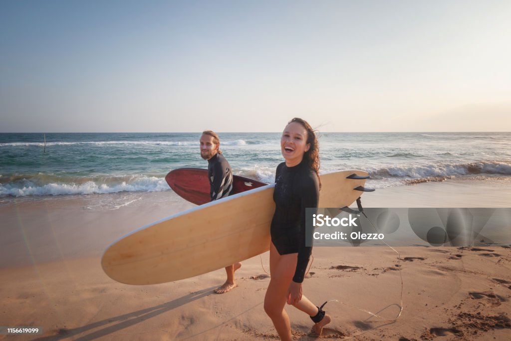 Young couple happy smiling surfers on ocean coast, sport active lifestyle vacation travel concept Young couple of happy smiling surfers on ocean coast, sport active lifestyle vacation travel concept Australia Stock Photo