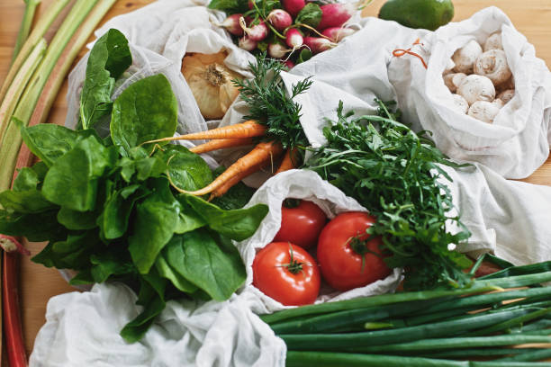 istock Reusable eco friendly bags with fresh vegetables carrots,tomatoes, spinach,arugula, mushrooms,rhubarb,onions on wooden table. ban plastic.Zero waste grocery shopping concept 1156620664