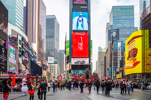 USA, New York, Times Square. May 2, 2019. High modern buildings, colorful neon lights, large commercial ads and people in a spring day