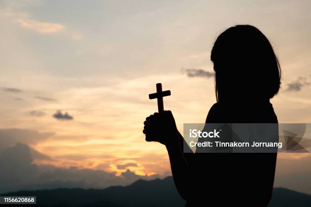 Silhouette Of A Young Girl Holding A Crucifix To God Morning With Beautiful Sunrise Symbol Of Faith Christian Life Prayer Crisis To God Stock Photo - Download Image Now