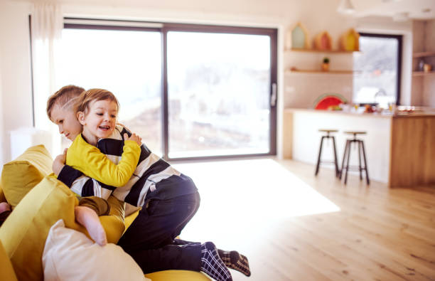 istock Two happy children sitting on sofa indoors at home, hugging. 1156626566