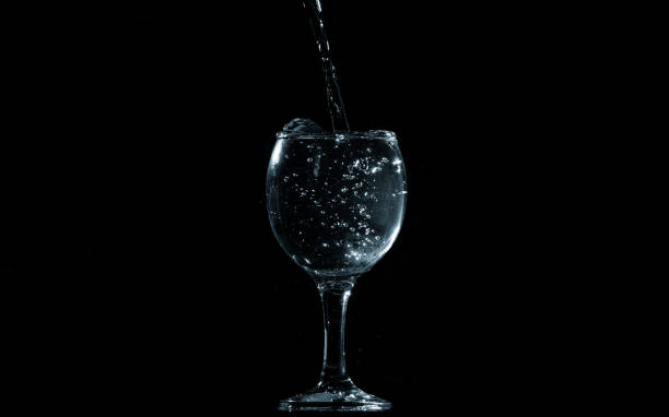 istock Pour water into glass on black background. 1156632783