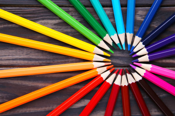 istock Many different colored pencils on brown wooden background 1156637131