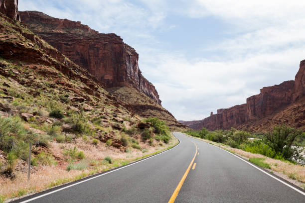 istock Open road stretches between red rock canyons trailing Colorado river 1156638782