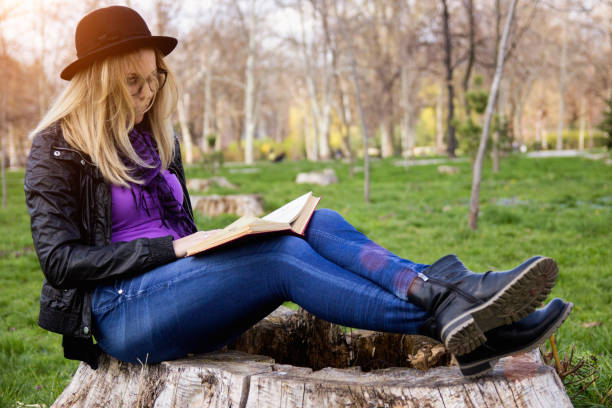 istock girl reading book at park in summer sunset light 1156639139