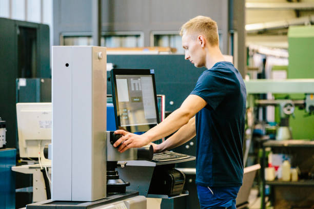 industry 4.0: young engineer control his work on a cnc machine - trainee mechanic engineer student imagens e fotografias de stock