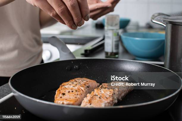 Fried Salmon Cooking On The Hob And Adding Herbs And Spices Stock Photo - Download Image Now