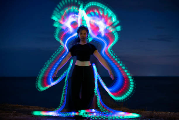 istock Young woman standing in front of light trail. 1156642238