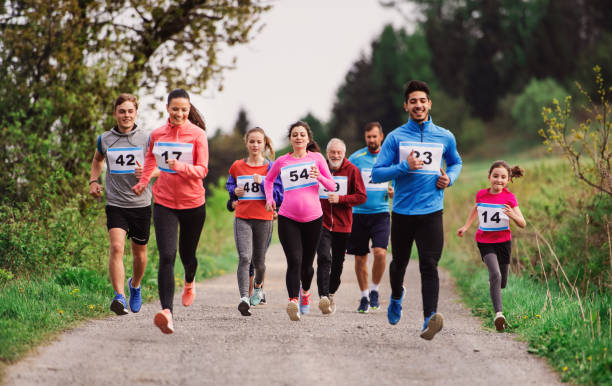 große gruppe von mehrgenerationen-menschen, die einen rennwettbewerb in der natur laufen. - marathon stock-fotos und bilder