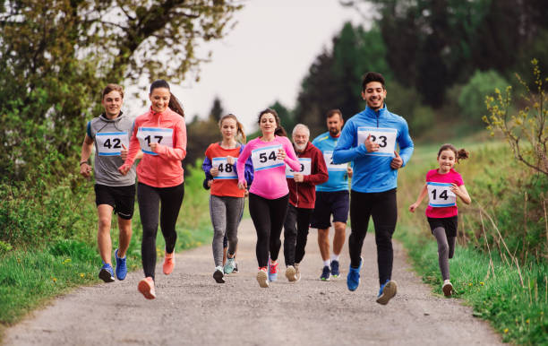 duża grupa wielopokoleniowych osób prowadzących zawody wyścigowe w przyrodzie. - jogging off track running women running zdjęcia i obrazy z banku zdjęć