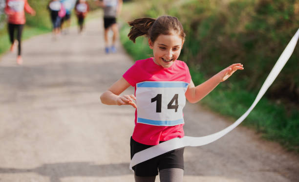 petite coureuse de fille franchissant la ligne d'arrivée dans une concurrence de course dans la nature. - jogging running athlete sport photos et images de collection