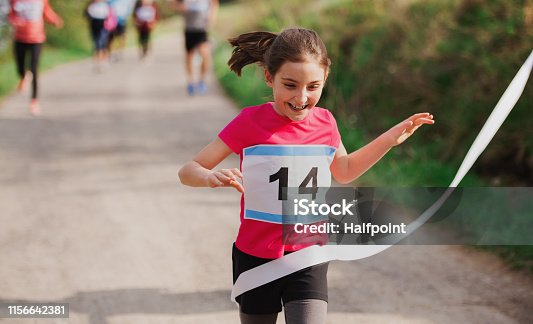istock Small girl runner crossing finish line in a race competition in nature. 1156642381
