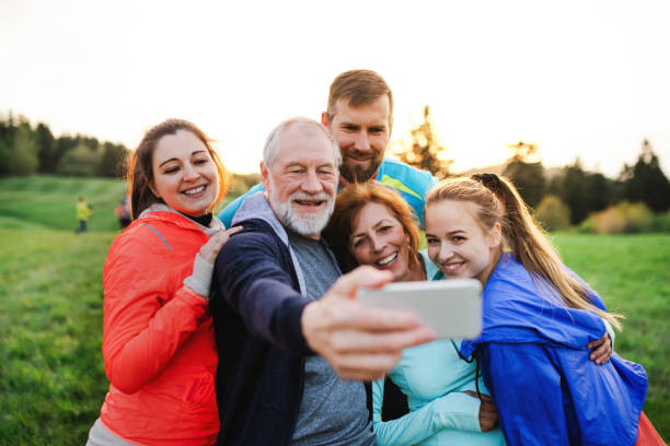 grupa fit i aktywnych ludzi odpoczywających po ćwiczeniach w przyrodzie, robiących selfie. - roots country zdjęcia i obrazy z banku zdjęć