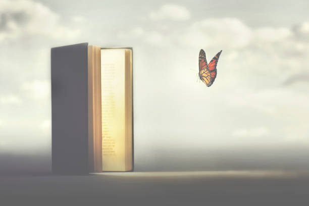 surreal moment of a butterfly entering the pages of a book stock photo