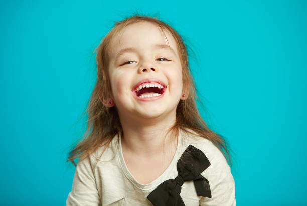 istock cheerful little girl laughs on blue background. 1156650101