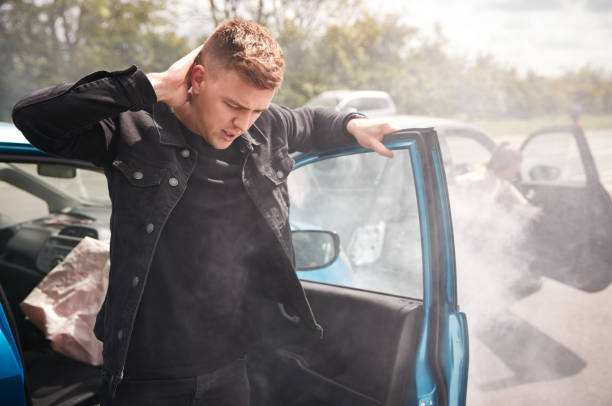 Male Motorist With Whiplash Injury In Car Crash Getting Out Of Vehicle Male Motorist With Whiplash Injury In Car Crash Getting Out Of Vehicle car accident stock pictures, royalty-free photos & images
