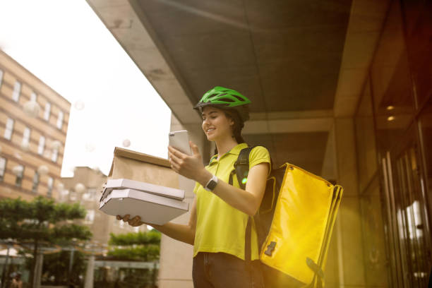 istock Young woman as a courier delivering pizza using gadgets 1156650592