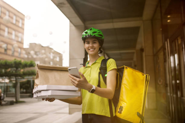 Young woman as a courier delivering pizza using gadgets