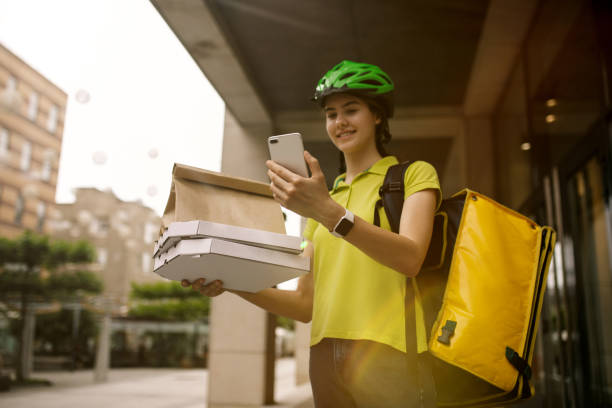 istock Young woman as a courier delivering pizza using gadgets 1156650597