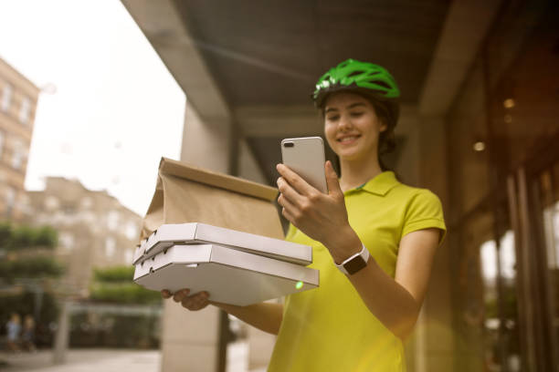 istock Young woman as a courier delivering pizza using gadgets 1156650614