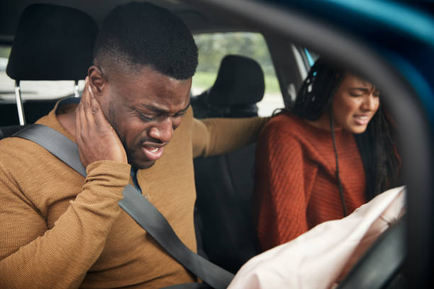 couples impliqués dans l'accident de voiture avec le conducteur masculin souffrant avec la blessure de coup de fouet - insurance physical injury transportation healthcare and medicine photos et images de collection