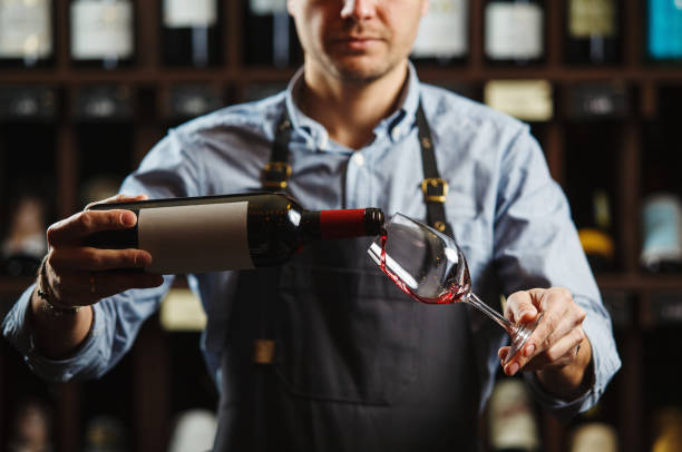 sommelier masculino que derrama o vinho vermelho em wineglasses longo-stemmed. - wine red wine glass bar counter - fotografias e filmes do acervo