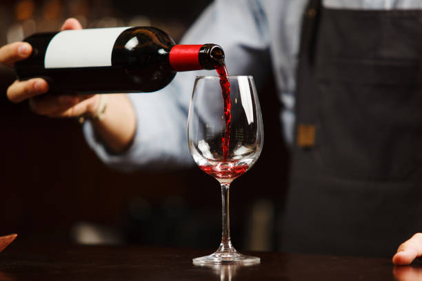 istock Bartender pouring red wine into wineglass. Sommelier pours alcoholic drink 1156654042