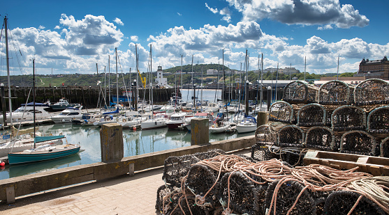 Scarborough harbour on a sunny summers day showing a range of boats and coastline and fishing equipment