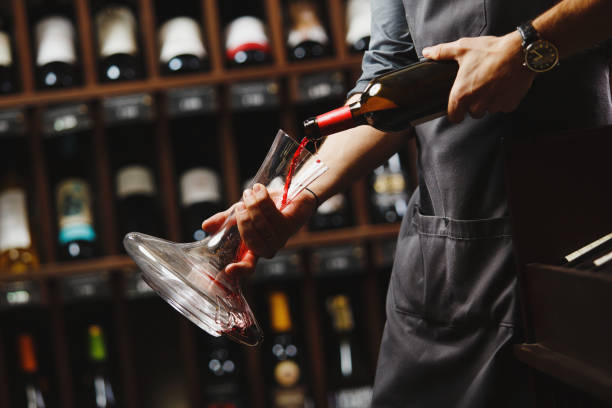 istock Bartender pours red wine in transparent vessel in cellar 1156657217