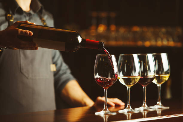 o bartender derrama o vinho vermelho nos vidros no contador de madeira da barra - wine red wine glass bar counter - fotografias e filmes do acervo