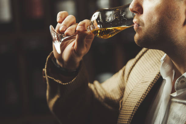 セラーの背景にウイスキーの味を味わうソムリエのクローズアップ写真。 - 味見する ストックフォトと画像