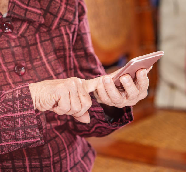 istock Asian elderly woman sitting and looking through something on modern smartphone, making connection with others at home, living technology, close up 1156662076