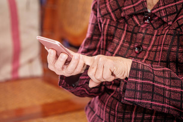 istock Asian elderly woman sitting and looking through something on modern smartphone, making connection with others at home, living technology, close up 1156662121