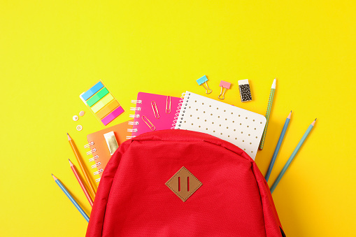 Flat lay composition with backpack and school supplies on color background