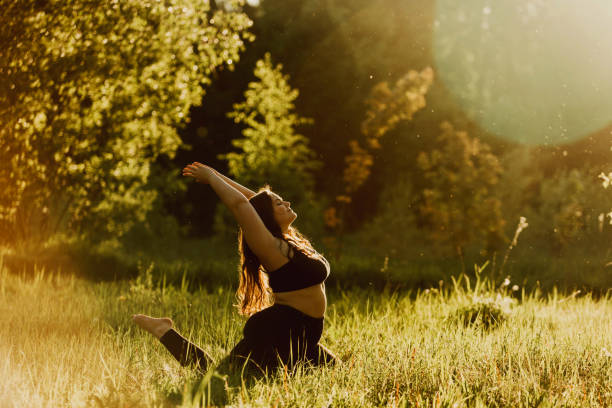 Beautiful plus size girl doing yoga in nature on a sunny summer day. Beautiful plus size girl doing yoga in nature on a sunny summer day. Body positive, sports for women, harmony, asana, healthy lifestyle, inspiring look, self-love and wellness. body confidence stock pictures, royalty-free photos & images