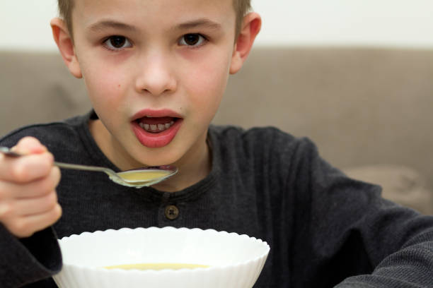istock Child boy eating soup from a plate with a spoon 1156667061