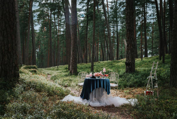 istock Romantic table setting with flowers and candles in the forest. 1156668490