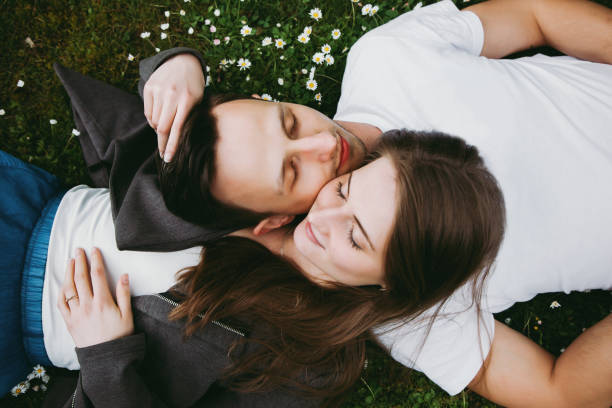 istock Young loving couple outdoors lying on grass, eyes closed, top down view. 1156668677