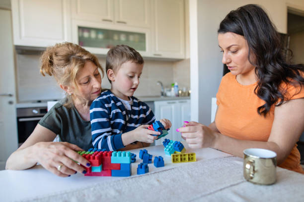 istock Boy playing with plastic blocks while his mom and grandma help 1156668702