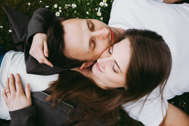 istock Young loving couple outdoors lying on grass, eyes closed, top down view. 1156668939