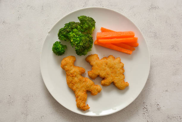 Kids food. nuggets with vegetables. Dinosaur shaped chicken, fish or turkey nuggets, ready to eat. Kids food. Dinosaur shaped chicken, fish or turkey nuggets, ready to eat. nuggets heat stock pictures, royalty-free photos & images