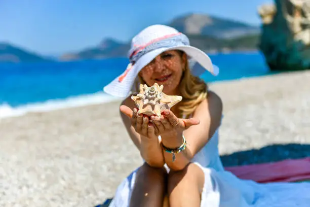 Photo of Woman on the beach handed out starfish.