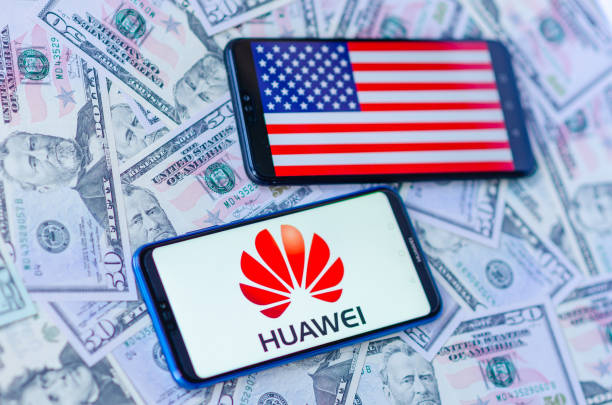 the close up photo of two mobile phones on dollar bills with chinese huawei logo and american flag. the conceptual editorial photo shows us china trade war. - war criminal imagens e fotografias de stock