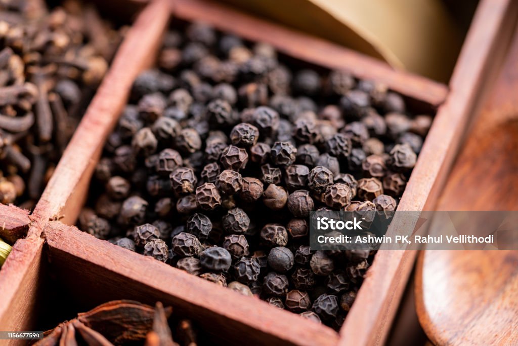 Black pepper in a box of spices Close up of Raw, natural, unprocessed black pepper in a box of spices Black Peppercorn Stock Photo